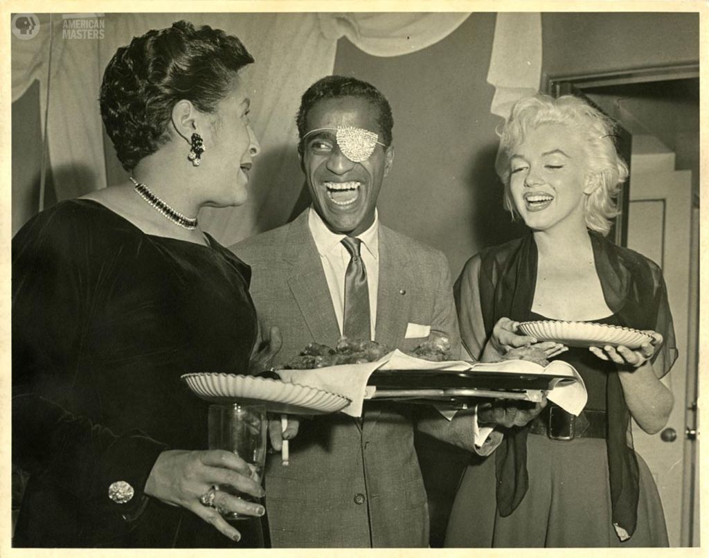Sammy Davis, Jr. and his fancy eyepatch laughing with Elvera Davis and Marilyn Monroe