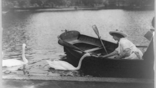 Helen Keller in a rowboat feeding a swan.