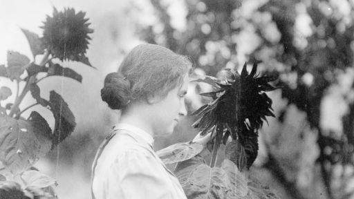 Helen Keller touching a large plant.