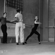 George Balanchine leaning against a ballet bar during rehearsal.
