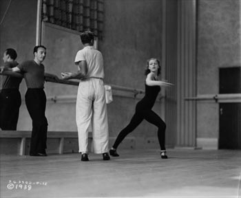 George Balanchine leaning against a ballet bar during rehearsal.