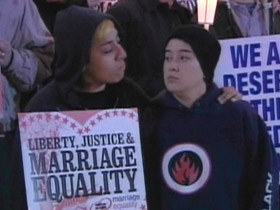 Couple holding marriage equality poster